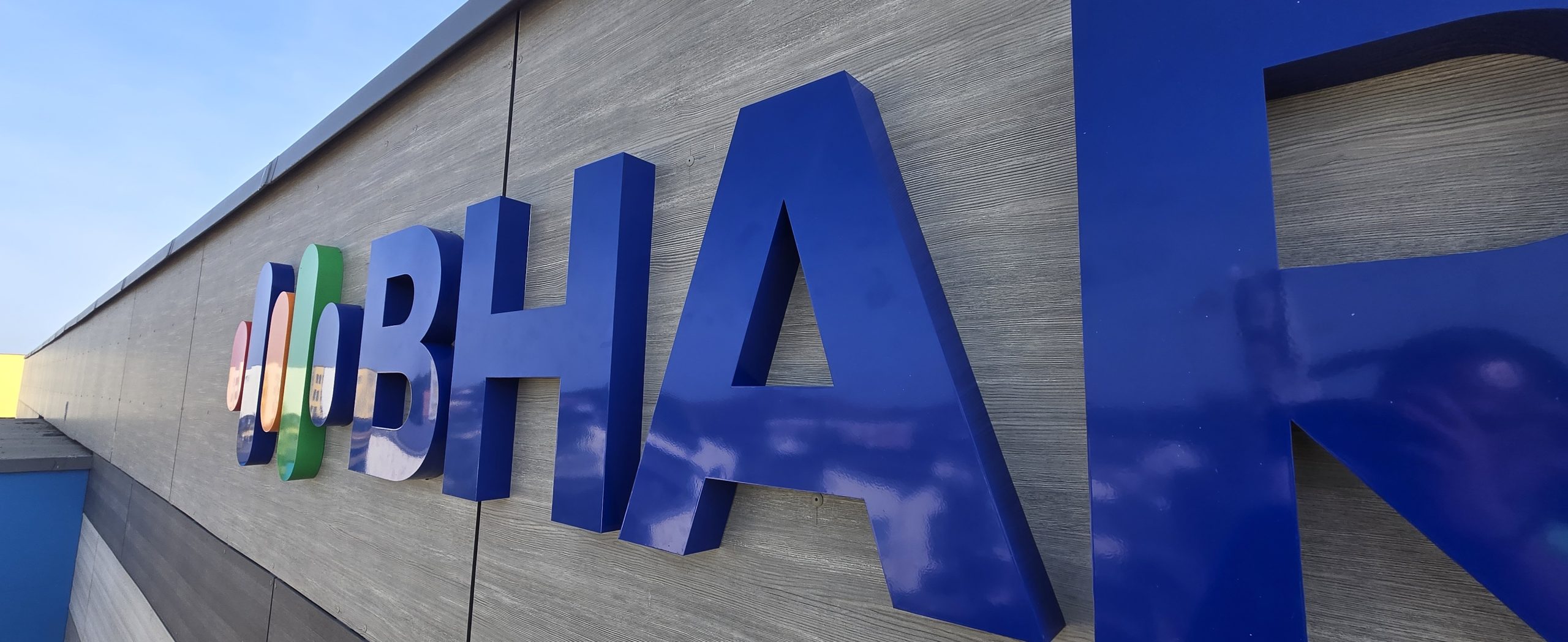 Close-up of blue built-up Bharani Health Hub letters fitted to grey exterior cladding