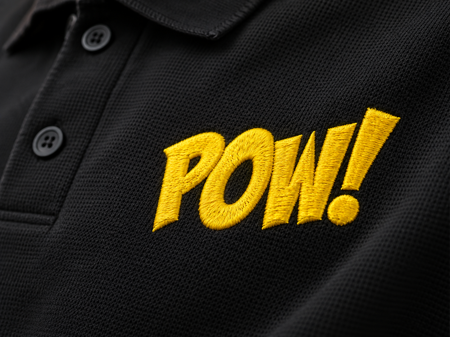 Close-up of raised yellow embroidery stitches on a black polo